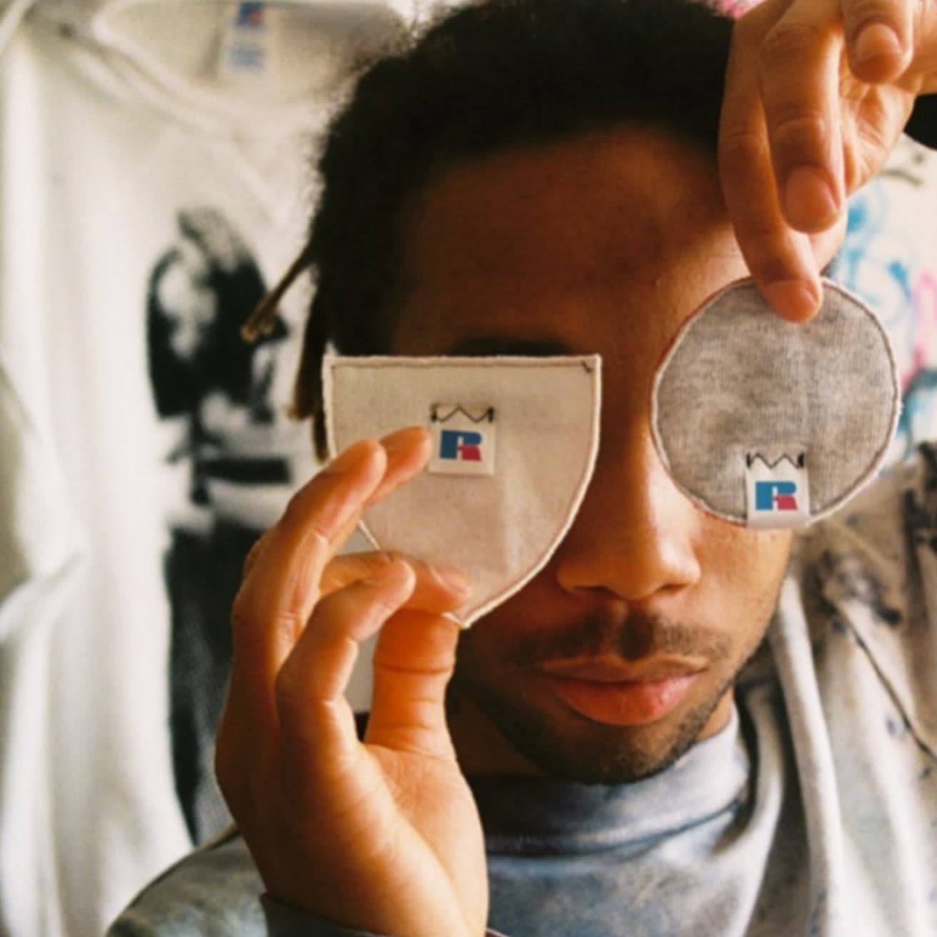 Two side-by-side photos: left, a person holding two cut cotton swatch patches with the Russell R logo over one eye; right, a vintage 'WOR… (1 of 2)