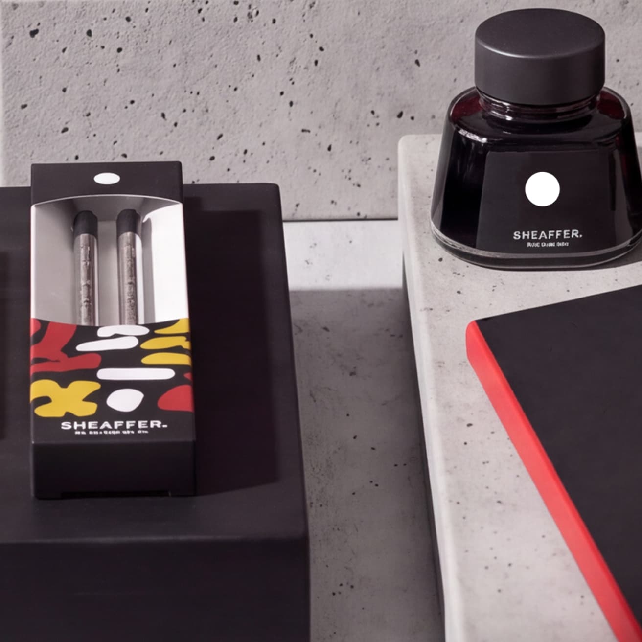 Sheaffer ink bottle with white dot and a boxed pair of ink refills on concrete (1 of 2)
